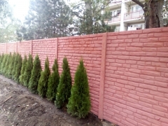 Betonový plot v červené barvě kolem cesty